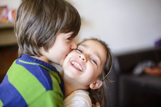 children brothers kiss on the cheek laughing and playing at home