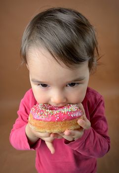 Little girl eating tasty donuts