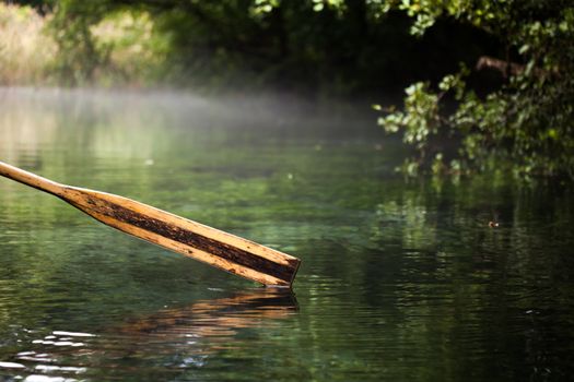 old wooden paddle (oar) from a row boat in a misty water