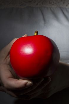 Red ripe apple in hands on a background of dress with lace