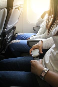 woman hands fasten belts while sitting on airplane seat.