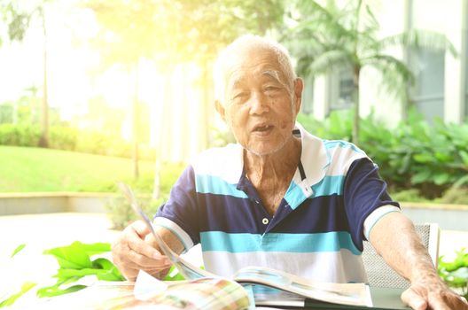 Asian senior man in the restaurant,ordering food by looking at the menu.