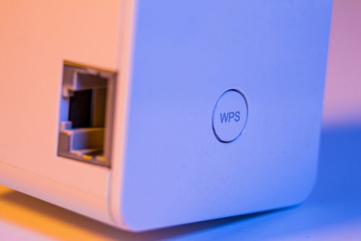 Closeup on WiFi repeater WPS button and ethernet socket. The device is in electrical socket on the wall. It help to extend wireless network in home or office.