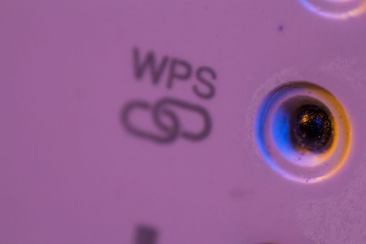 Macro closeup on WPS symbol signal connection status led light. The WiFi repeater device is in electrical socket on the wall. It help to extend wireless network in home or office.