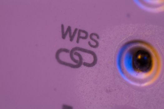 Macro closeup on WPS symbol signal connection status led light. The WiFi repeater device is in electrical socket on the wall. It help to extend wireless network in home or office.