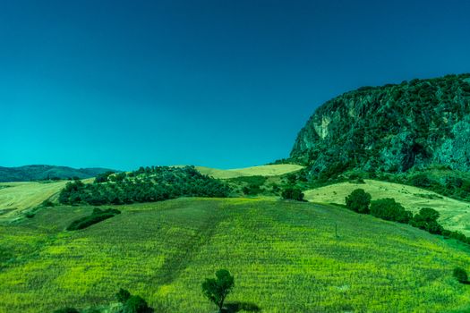 Greenery, Mountains, Farms and Fields on the outskirts of Ronda Spain, Europe on a hot summer day with clear blue skies