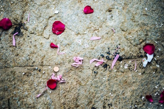 stone background with rose coin petals and colorful rose and rice paper threads thrown for a wedding