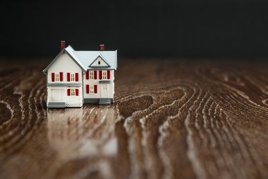 Model Home on Reflective Wooden Surface.