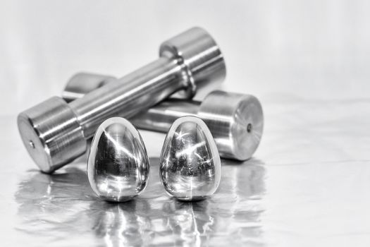 Metal dumbbells and steel eggs, the concept of sports training and the achievement of muscle strength.