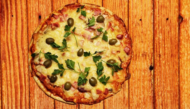 Pizza with sausage and olives decorated with parsley.