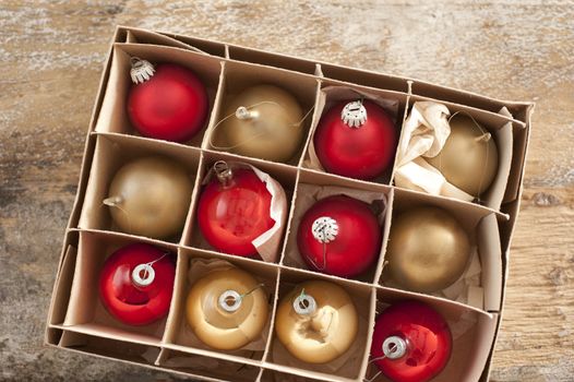 Top down view on golden colored and red christmas tree ornament balls inside cardboard box