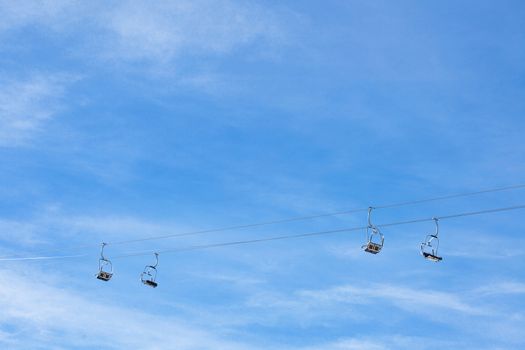 ski chair lift with two cables and four double seats, against blue sky