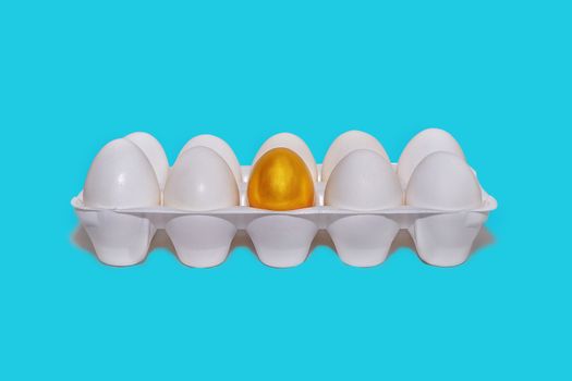 Tray with white eggs, one gold, the concept of the beginning of financial success