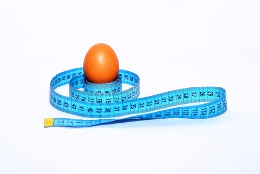 Egg wrapped in blue measuring tape, slimming concept.