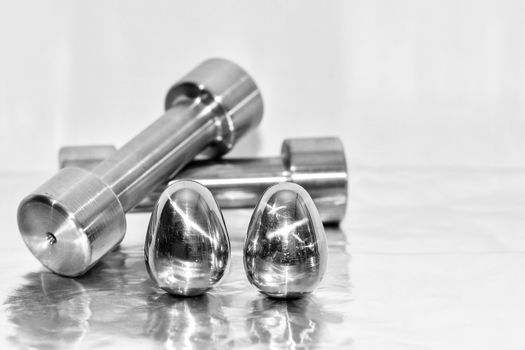 Metal dumbbells and steel eggs, the concept of sports training and the achievement of muscle strength.