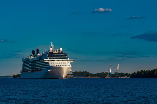 Giant white passenger ship moving past the port on a clear day