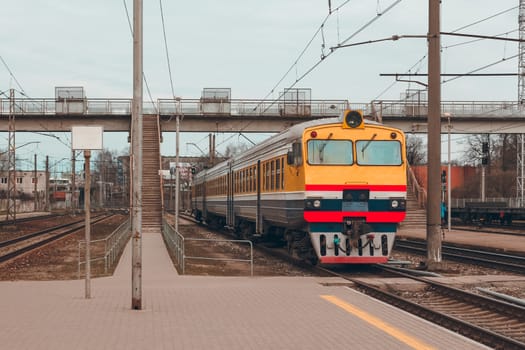 Old yellow passenger diesel train moving at the terminal