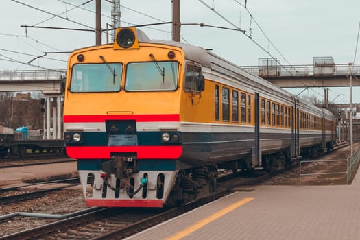 Old yellow passenger diesel train moving at the terminal