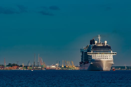 Giant white passenger ship moving past the port on a clear day