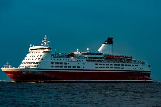 Red cruise liner. Passenger ship sailing from the sea in the morning