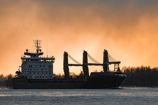 Black bulk carrier sailing to the sea in cold winter