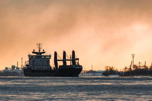 Black bulk carrier sailing to the sea in cold winter