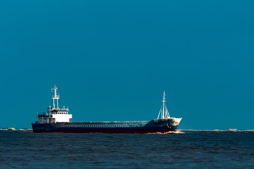 Blue bulk carrier moving from the sea in cold winter