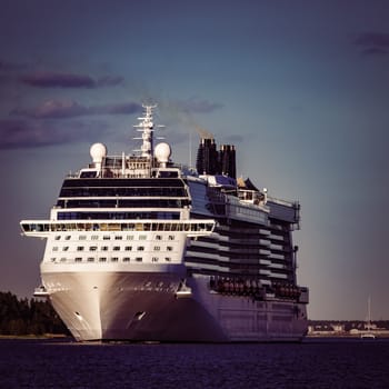 Giant white passenger ship moving past the port on a clear day