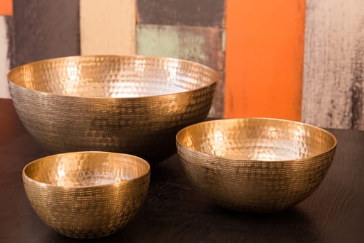 Three empty decorated metal bowls on a table