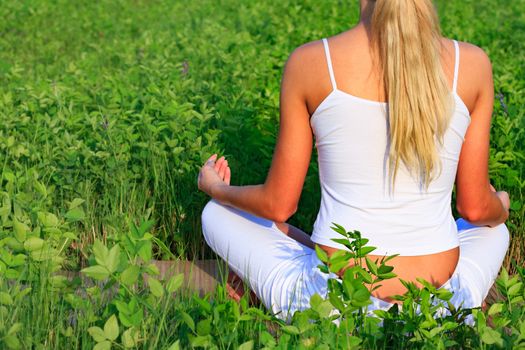 Yoga woman sitting in green grass