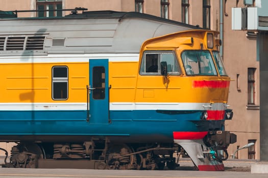 Old yellow passenger diesel train moving at the terminal