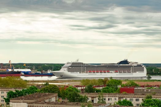 Big white cruise liner sailing past the cargo port