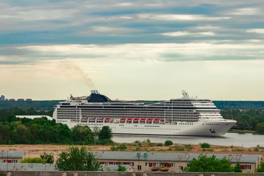 Big white cruise liner sailing past the cargo port