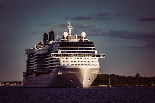 Giant white passenger ship moving past the port on a clear day