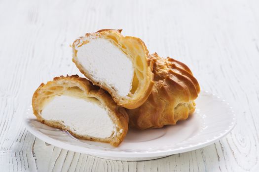 Profiteroles on plate on a table on wooden background