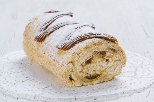 Biscuit roll with condensed milk on a table, selective focus