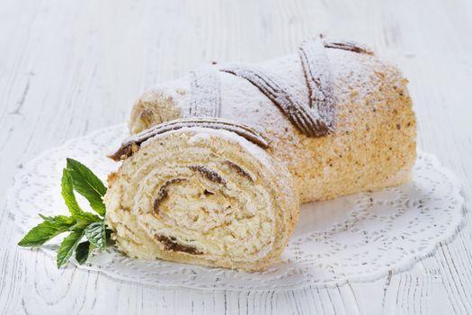 Biscuit roll with condensed milk on a table, selective focus