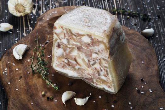 Headcheese on a slate cutting board on wooden background