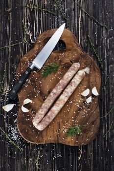 Raw sausages with garlic and parsley on the cutting board