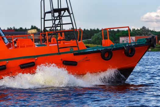 Orange pilot boat moving by the river in Europe. Rescue service