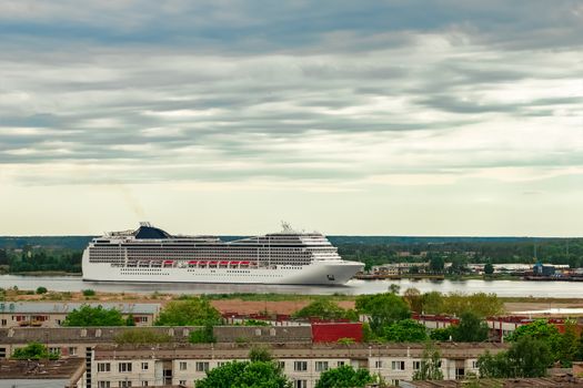 Big white cruise liner sailing past the cargo port