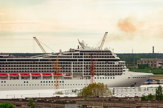 Big white cruise liner sailing past the cargo port