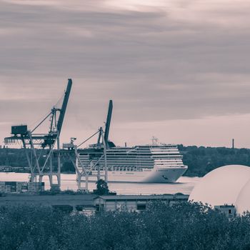 Large cruise liner sailing past the cargo port. Monochrome