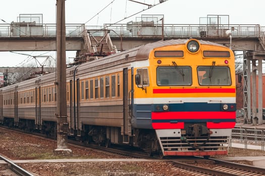 Old yellow passenger electric train driving at the terminal