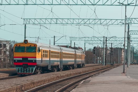 Old yellow passenger diesel train moving at the terminal