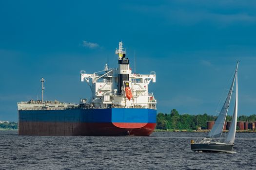 Merchandise import. Large blue cargo ship moving to Riga port