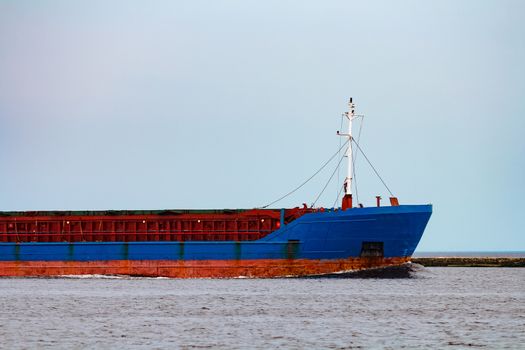 Merchandise import. Large blue cargo ship moving to Riga port