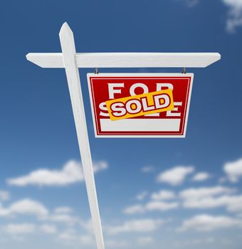 Right Facing Sold For Sale Real Estate Sign on a Blue Sky with Clouds.