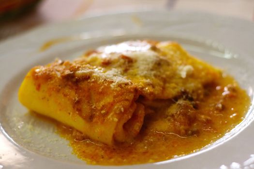 Lasagna in Restaurant on a white plate with parmigiano cheese on top
