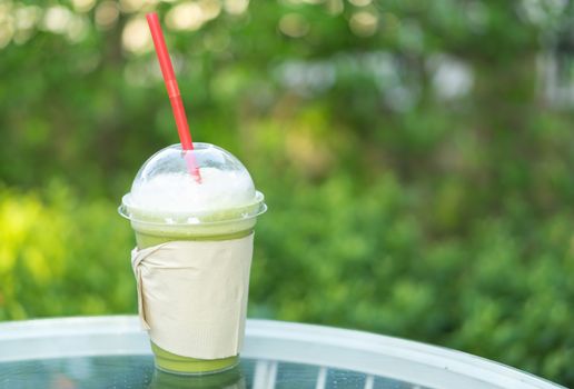 Closeup glass of ice matcha green tae with nature background, selective focus